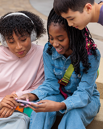 Lifestyle image of three kids looking at a phone together