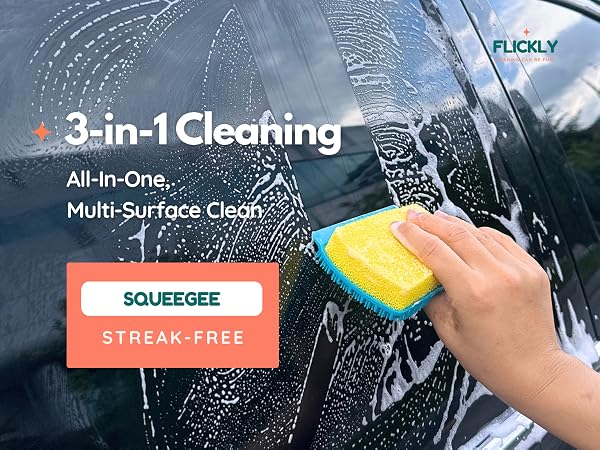 Hand using a sponge with squeegee edge to clean a soapy car window, demonstrating streak-free finish