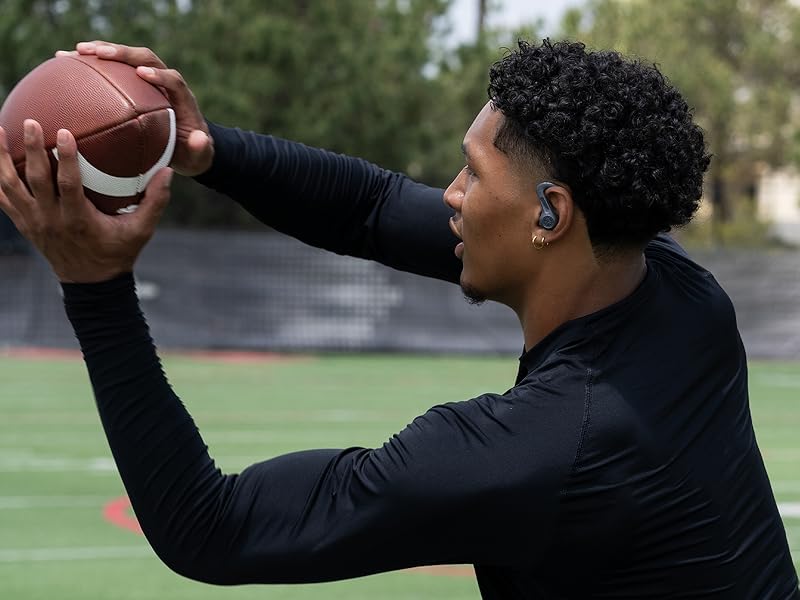 Athlete catching football while wearing jbuds sport