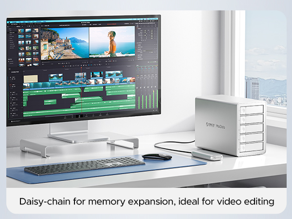 Video editing workspace with large monitor showing editing interface, wireless keyboard, and white external storage device with daisy-chain capability for memory expansion.
