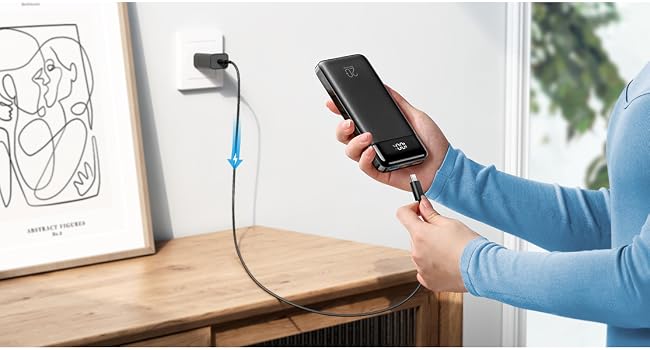 Wall-mounted phone charging setup with blue cable next to minimalist line drawing artwork on desk.