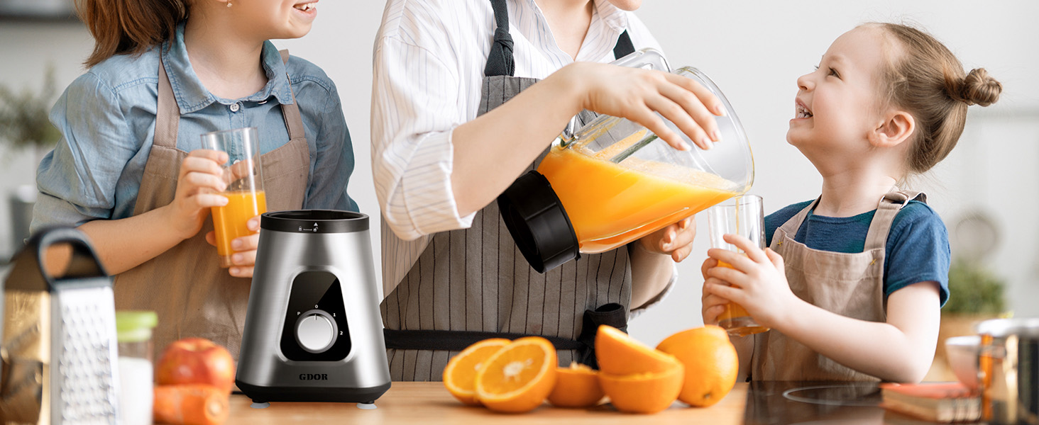 Stainless steel and black electric juicer on counter with fresh oranges. Adult pouring fresh orange juice into child's glass, demonstrating product use in family kitchen setting.