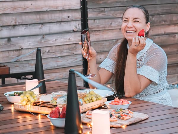 Woman enjoying outdoor dining with Fly Away fans keeping flies away from food on a patio table.