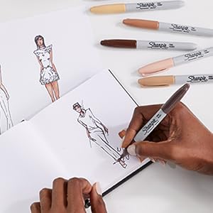 Someone sketching a person in a sketchbook using Sharpie Portrait Markers