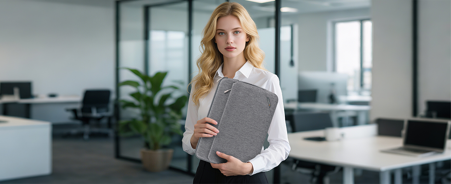 Modern office setting showing someone holding what appears to be a grey tablet or device case in a bright, minimalist workspace with plants.