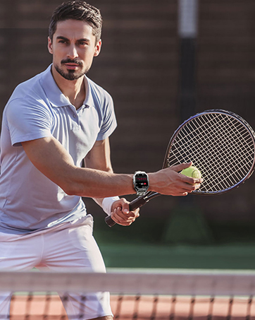 Tennis player on court wearing white attire, holding tennis racket in ready position with focused athletic stance.