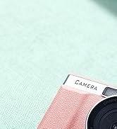 Text reads 'CAMERA'. Close-up view of a pale mint green and pink textured surface with partial view of camera-related equipment.