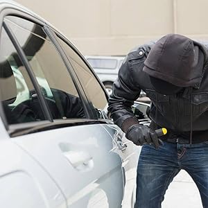 a person with a black hood is breaking into a car.