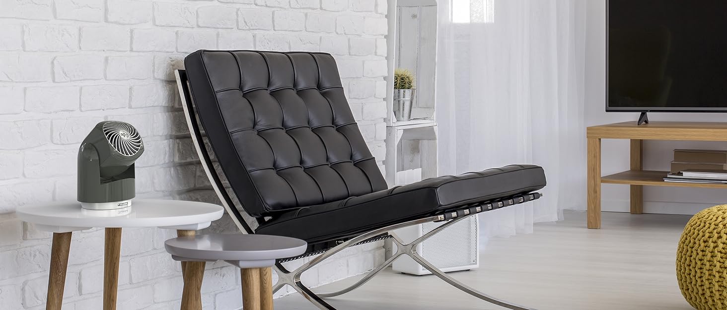 Gray personal Flippi fan on side table next to modern black leather chair
