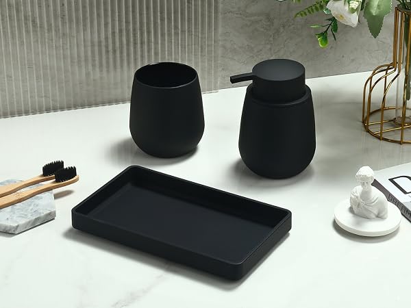 Black bathroom accessories set including two round containers, a rectangular tray, and wooden toothbrushes on a white surface. Minimalist design with matte finish.