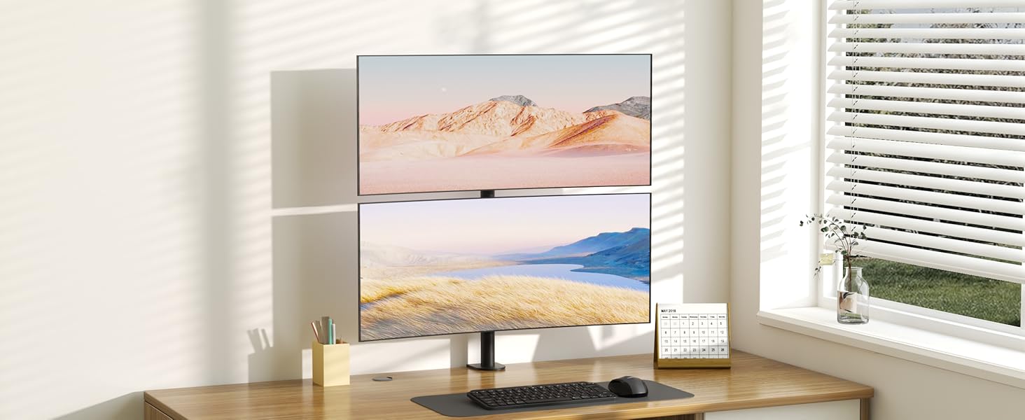Modern flat-screen TV mounted above a wooden desk, displaying desert landscape images against a white wall with window light.