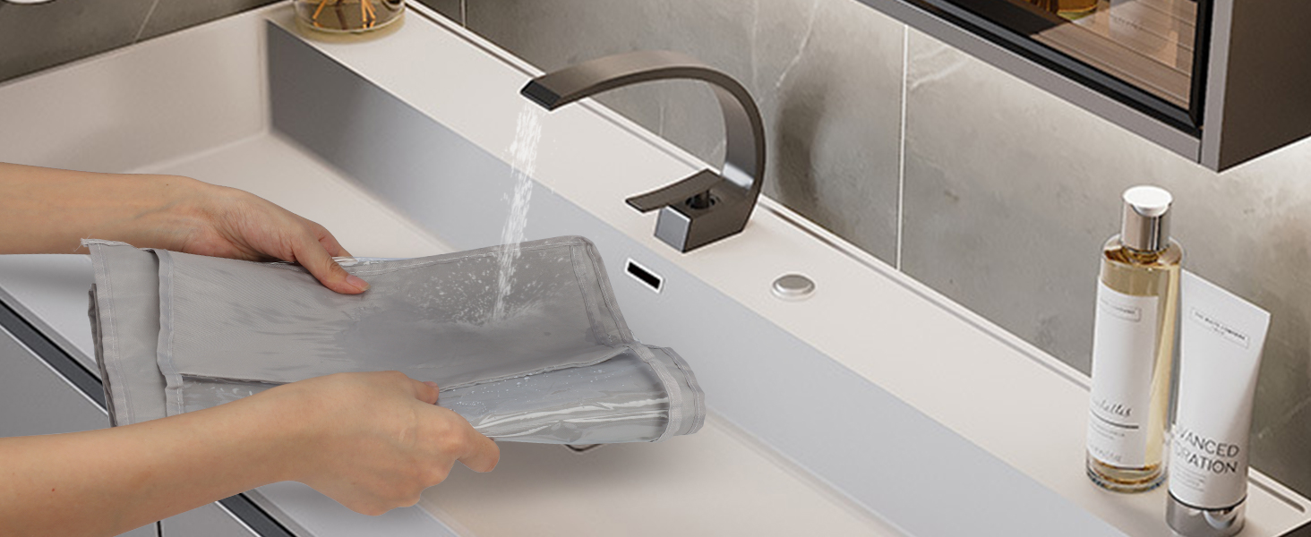 Hands demonstrating a kitchen faucet with pull-down sprayer. Water streams from the nozzle into a clear container over a white sink.