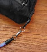 Close-up of a blue braided cord with metal clip attachment connected to black fabric, showing detail of connection point on wooden surface.