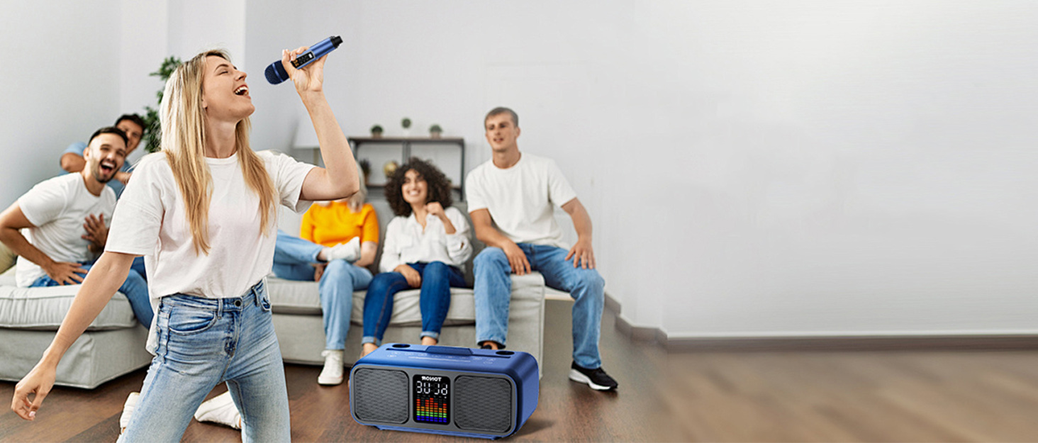 Blue portable speaker system being used during an indoor gathering, with display screen and microphone functionality visible.