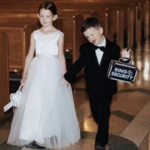 Ring bearer holding ring security briefcase with flower girl walking down the wedding aisle