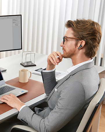 a man sitting at a desk with a laptop and a monitor