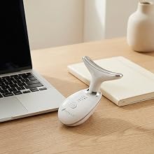 LED skincare device resting on desk beside laptop