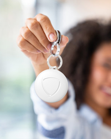 Hand holding up a white circular device or token against a blurred background, demonstrating its size and portable nature.