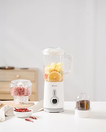 Compact white personal blender on light countertop with citrus fruits and ingredients nearby. Clean, minimalist kitchen setting with natural lighting.