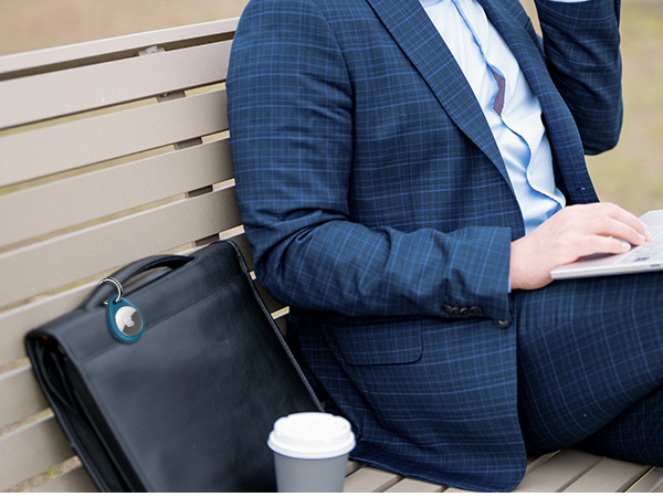 Person in blue suit sitting on wooden bench with black leather briefcase and white coffee cup nearby. Focus on torso and lap area.