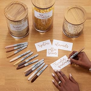 Person writing with Sharpie Portrait Markers and additional markers on table