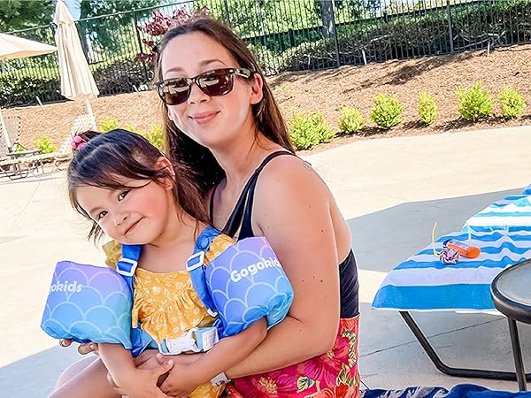 Mother and daughter smiling with beach chairs in the background that are covered in beach towels