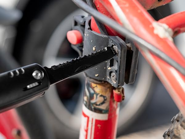Close-up of a bicycle pedal and crank arm, showing the chain and gear mechanism. The frame appears to be red.
