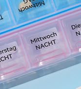 Close-up of a blue plastic pill organizer with labeled compartments for different days and times.