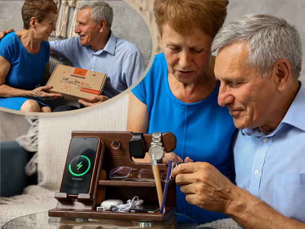 Wooden organizer tray with compartments holding various items including a watch, phone charging wirelessly, and eyeglasses. Visible on a couch or chair.