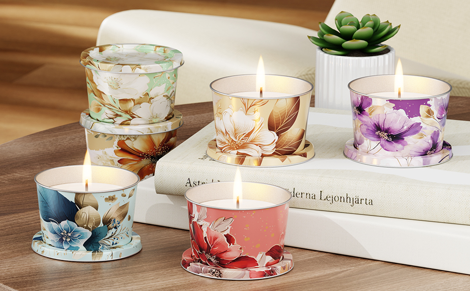 Collection of decorative glass candle holders with floral designs in different colors - blue, pink, purple, and peach. Each holder features painted flowers and contains a lit candle.