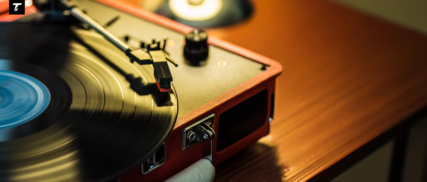Vintage record player with tonearm on a vinyl record. Wooden base and blue record visible, demonstrating analog music playback.