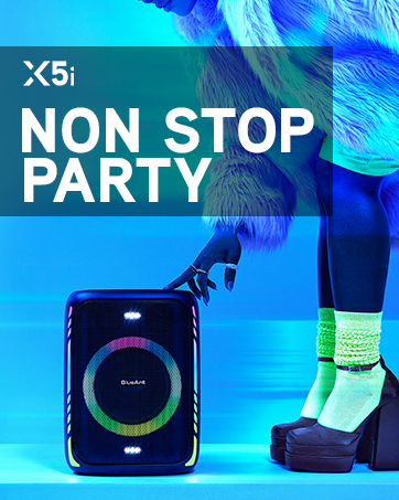 BlueAnt X5i Party Speaker. Woman in party clothes bends down to touch the X5i speaker