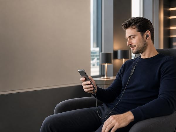 Close lifestyle view of black wired earbuds connected to a smartphone via USB-C