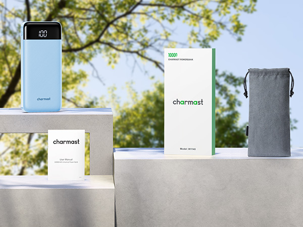 Outdoor display of electronic devices: a white power bank, packaging boxes, and a gray pouch, arranged on a concrete surface.
