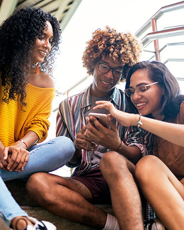 Lifestyle image of three women sitting looking at a phone together