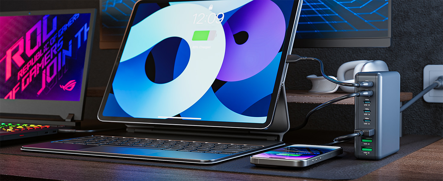 Desktop setup with illuminated laptop, iPad, smartphone, and charging device against dark background with purple and blue lighting effects.