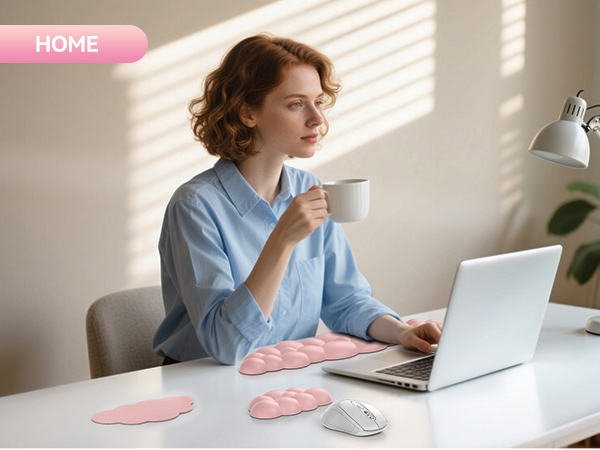 Pink cloud-shaped desk accessories on white table with laptop, mouse, and desk lamp. Woman in blue shirt using computer while holding coffee mug.