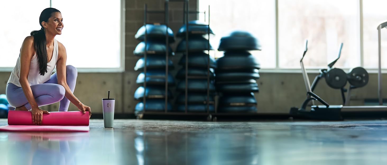 Woman with IronFlask water bottle rolling up yoga mat.