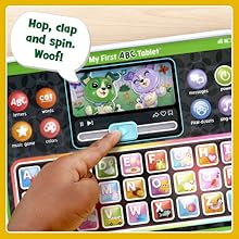 Kid slides slider under Scout and Violet graphic on toy tablet. Toy says: Hop, clap and spin. Woof!