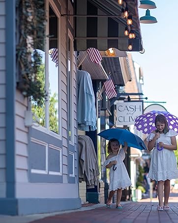 two children walking with kids uumbrellas past store front toward camera