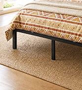 Beige/tan upholstered bench with geometric woven pattern placed on matching area rug in minimalist interior space.