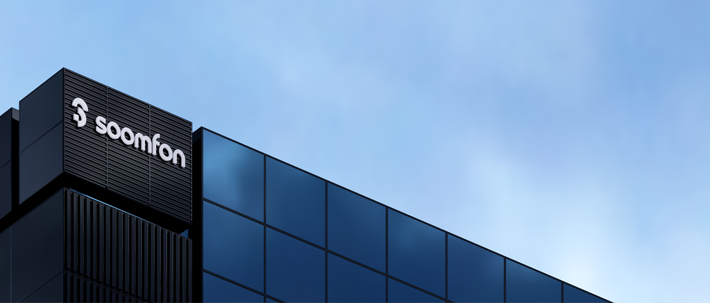 Exterior of a modern office building with blue sky background. Large 'Soomfon' sign visible on the dark facade.