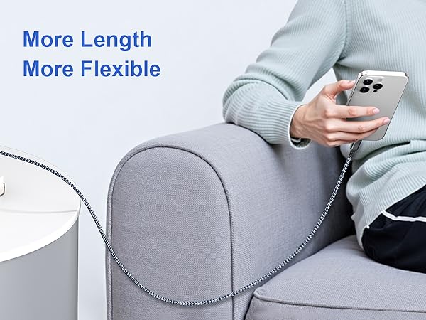 Long, flexible charging cable connected to a smartphone held by a person sitting on a gray couch. Text highlights 'More Length' and 'More Flexible' features.