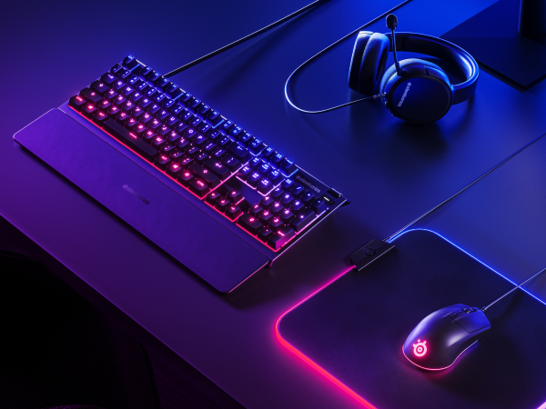 - A SteelSeries desk setup with Apex keyboard, Rival 3 mouse, Arctis headset, and QcK Prism mousepad