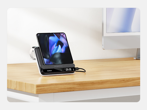 Black smartphone charging stand on wooden desk surface, displaying phone in horizontal viewing position with blue illuminated screen.
