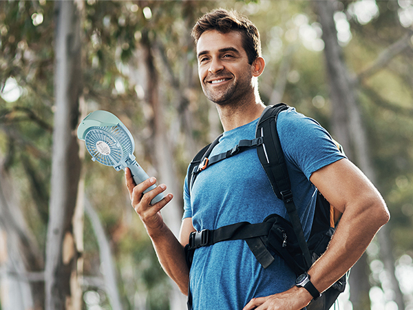 Outdoor scene of a person in blue shirt and backpack holding a map or device, surrounded by trees in a natural setting.