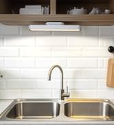 a kitchen sink with a light under the sink.