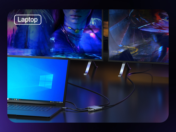 Laptop on a dark surface with illuminated screen showing Windows logo. Connected to external display in background with colorful lighting and DJ equipment visible.