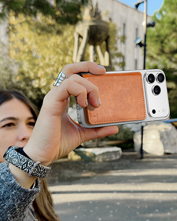 Orange leather phone case with multiple camera lenses shown being held and demonstrated in outdoor setting.