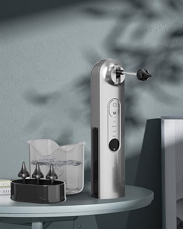 Silver metallic electric device with rotating head attachment displayed on a gray surface next to accessory components.